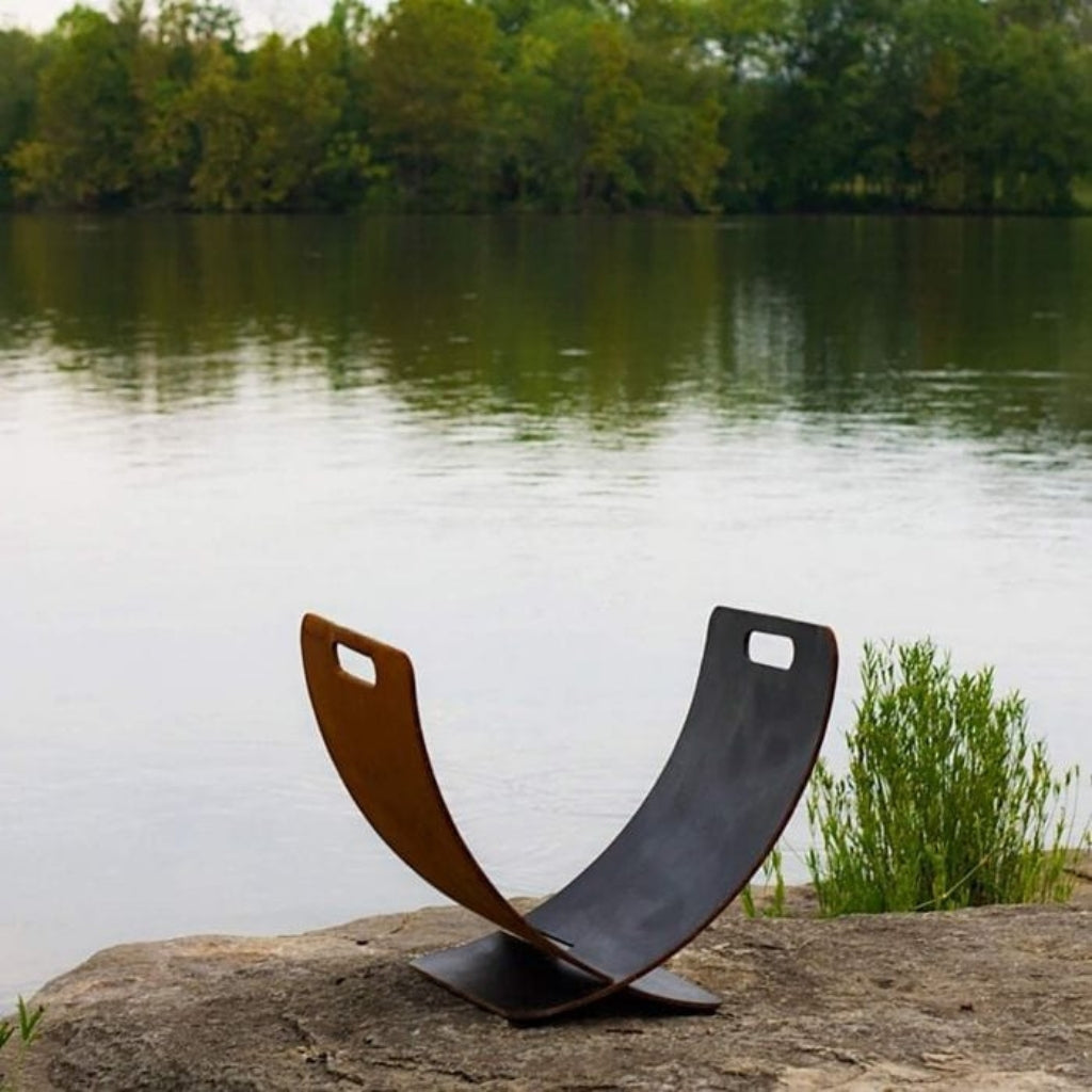 Modern carbon steel log rack with curved Wings of Flight design for stylish firewood storage